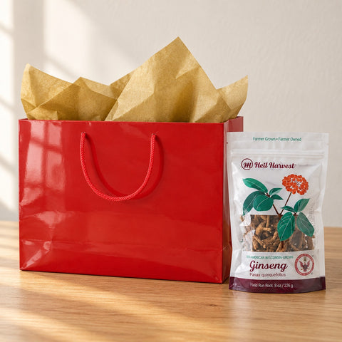 Red gift bag with gold tissue beside an 8 oz Heil Harvest ginseng pouch