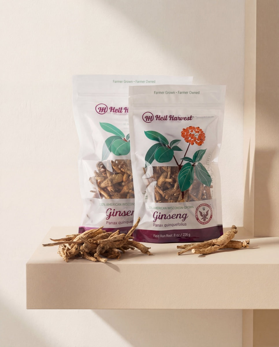 Two Heil Harvest Wisconsin ginseng packages styled with loose whole roots in soft daylight — a giftable presentation.