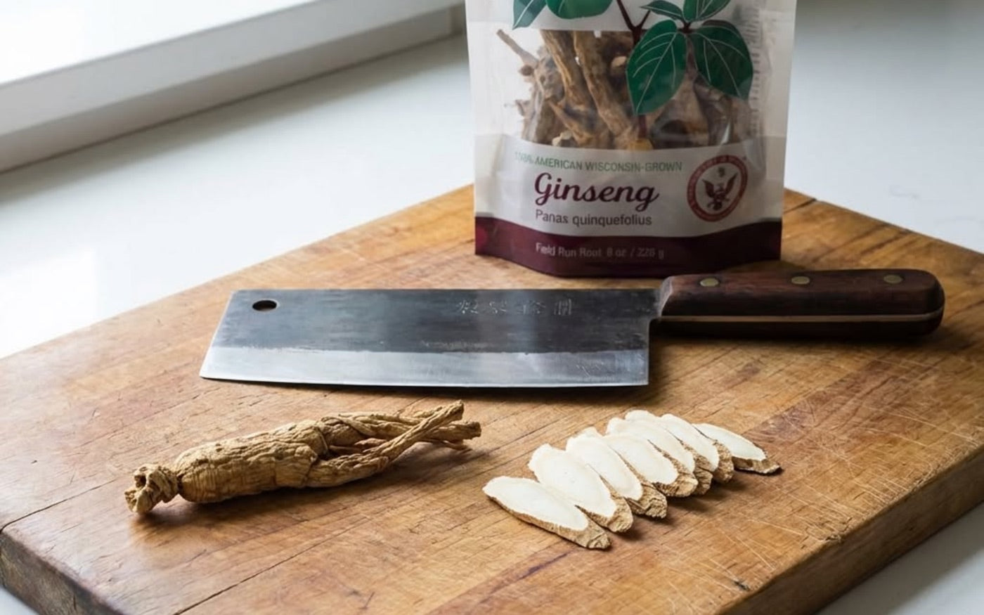 A whole Wisconsin ginseng root with fresh-cut slices on a kitchen board beside an 8 oz Heil Harvest pouch.